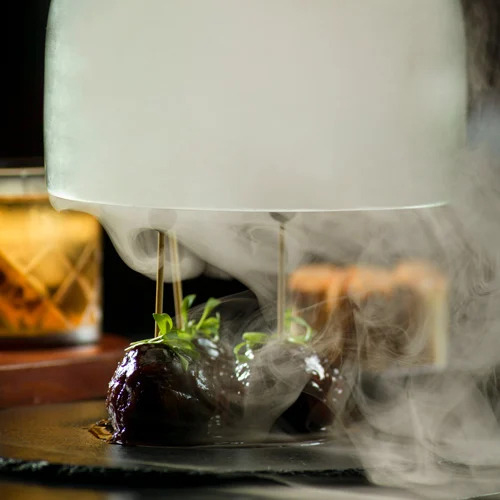 A plate with grilled meat skewers emitting smoke, creating an appetizing and smoky presentation.