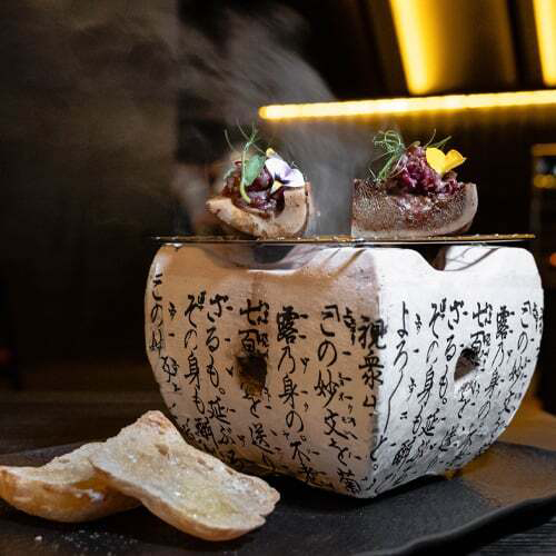 An authentic bowl with Japanese alphabets topped with a piece of bread and meats